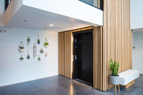 a lobby with a black door and wooden wall decorations on the wall