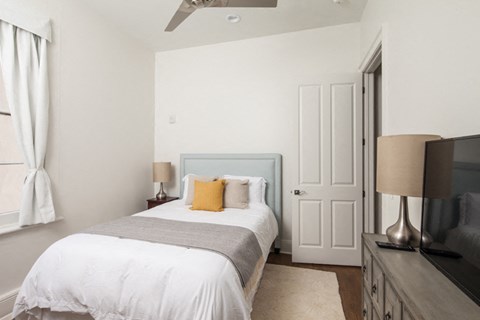 a bedroom with a bed and a dresser and a tv