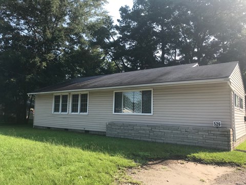 the front of a white house with a dirt road in front of it