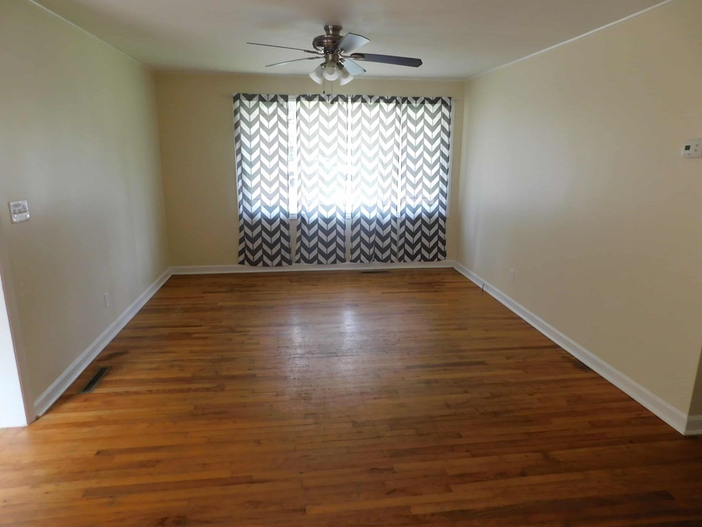 a living room with wood floors and a window with a curtain