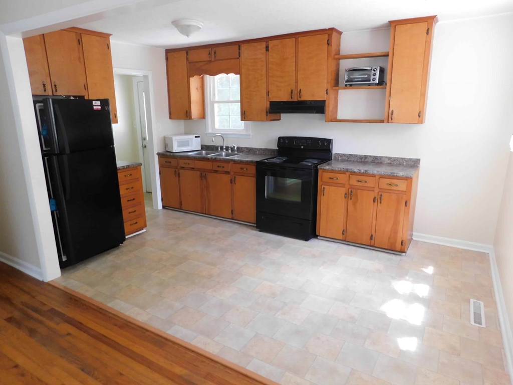 an empty kitchen with black appliances and wooden cabinets