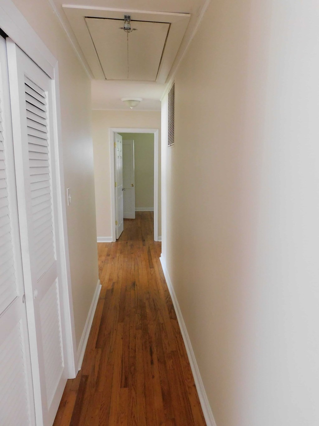 a hallway with wooden floors and white walls and white shutters