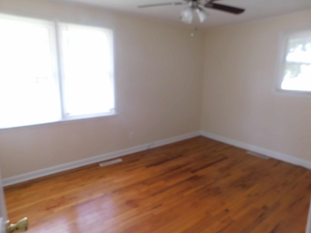 an empty room with wooden floors and a ceiling fan