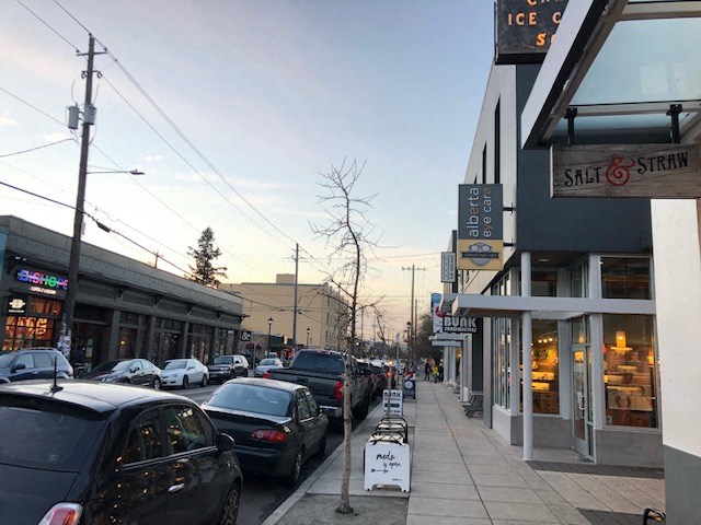 a busy city street with cars parked on the sidewalk