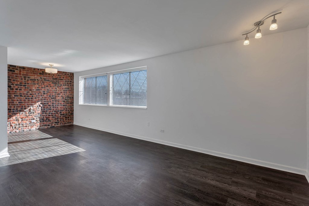 an empty living room with a brick wall and a window