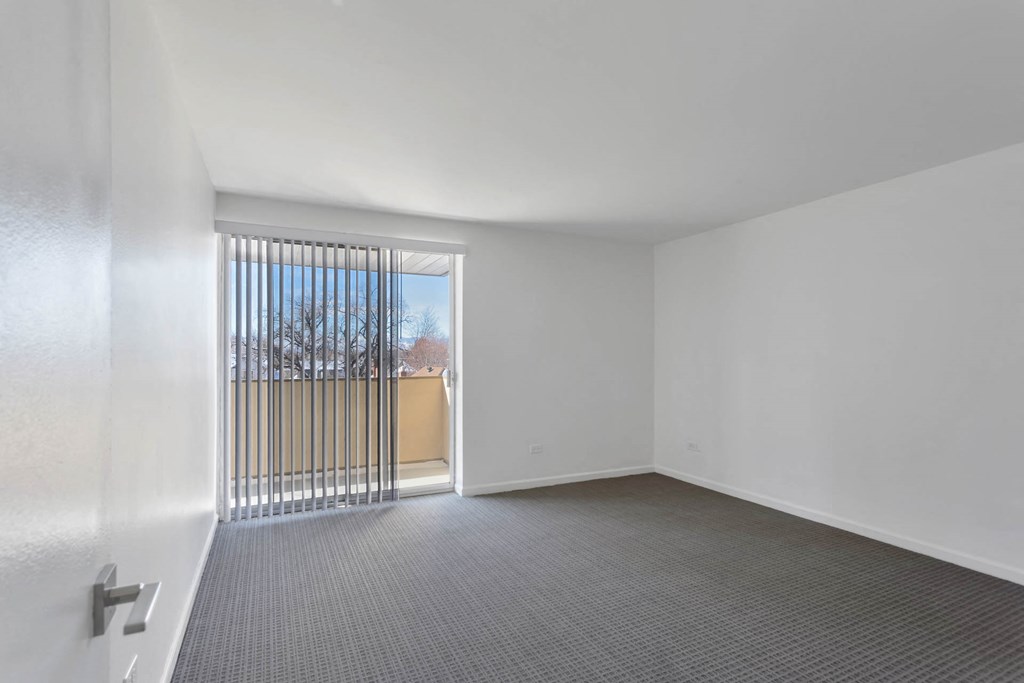 an empty living room with a sliding glass door to a balcony