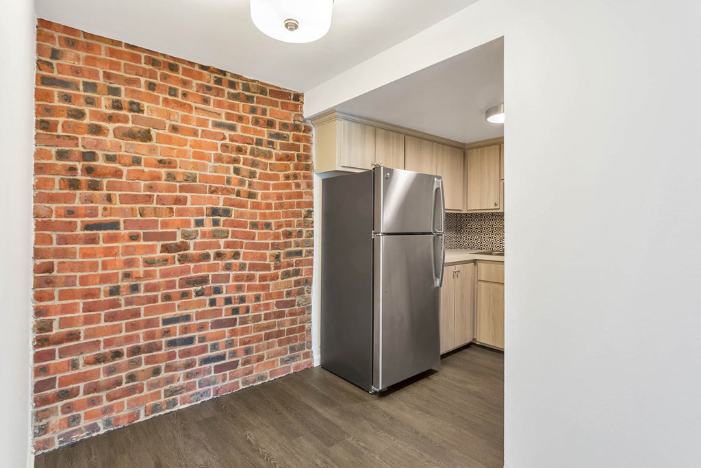 a kitchen with a stainless steel refrigerator next to a brick wall