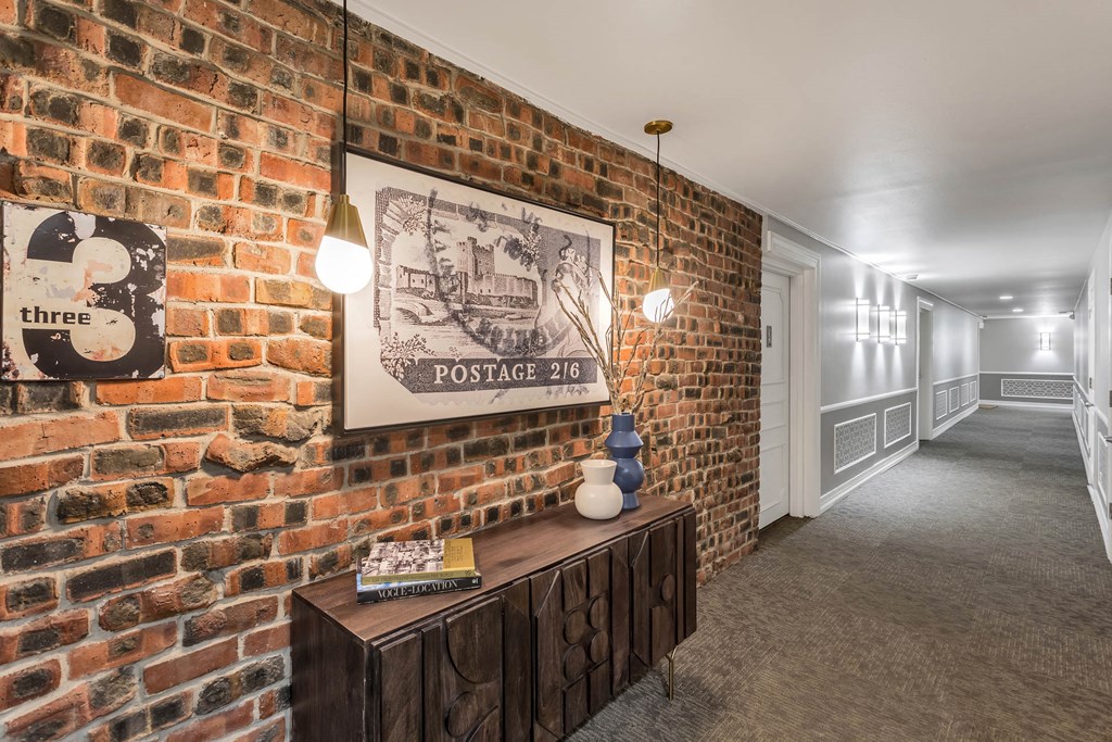 a long hallway with a brick wall and a painting on it