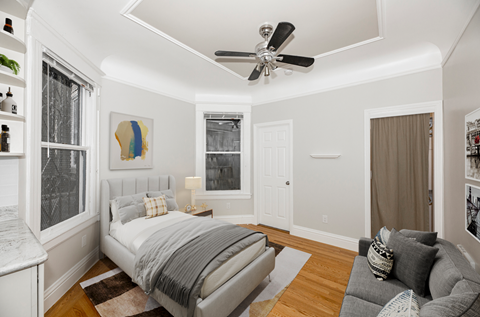 A bedroom with a bed, a couch, and a ceiling fan.