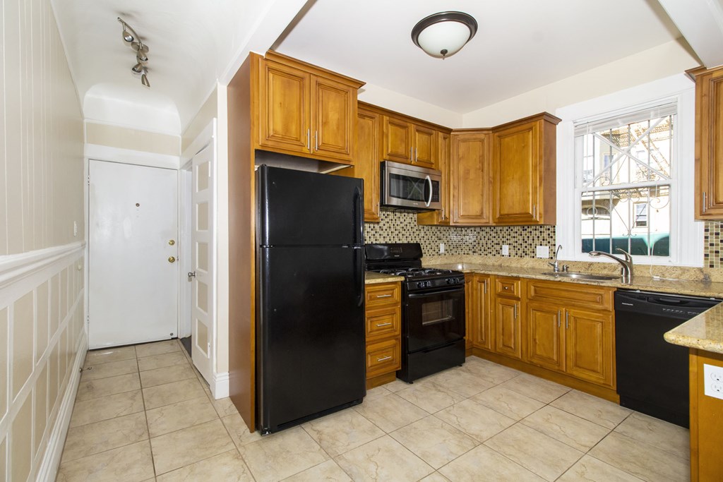 a kitchen with wooden cabinets and a black refrigerator