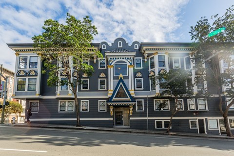 A large, ornate building with a blue and gold facade sits on a street corner.