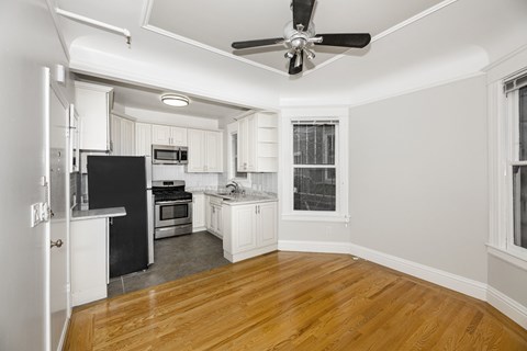 A kitchen with white cabinets and a black refrigerator.