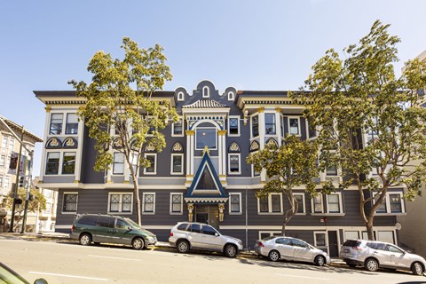 A grey building with a blue trim and a tree in front of it.