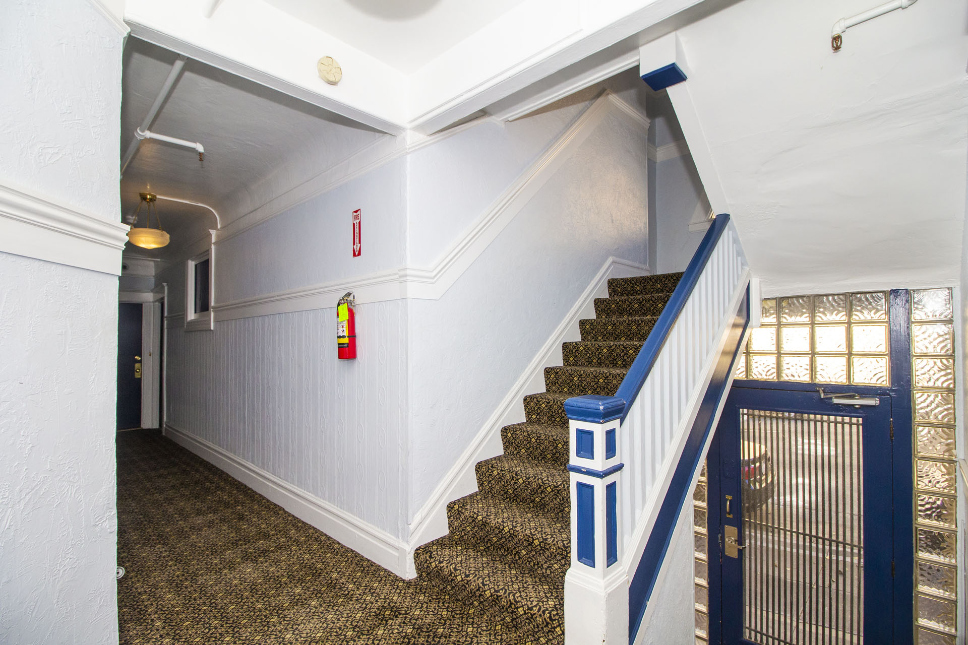 A staircase with a blue railing and a red fire extinguisher on the wall.