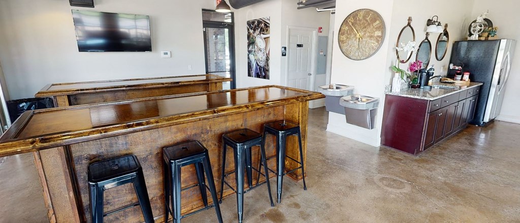 a bar with four stools in a room with a sink and a refrigerator