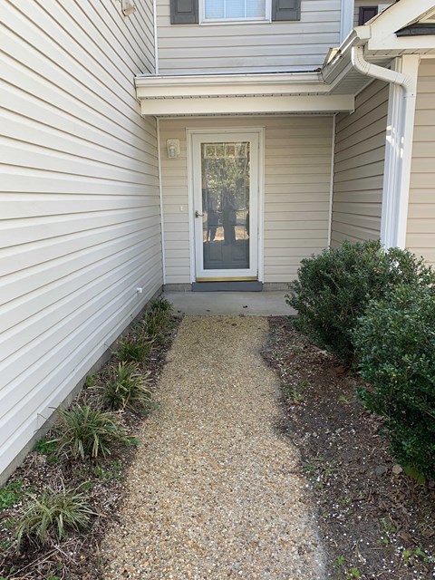 A white door is on the right side of a grey house.