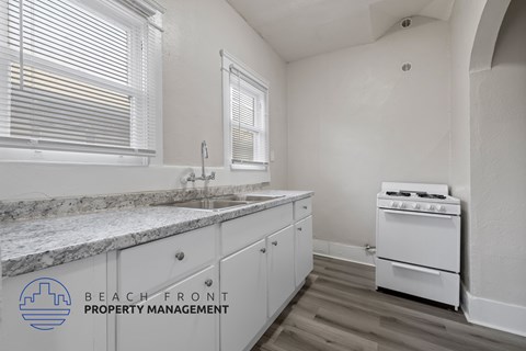 A kitchen with a white stove and cabinets with a logo for Beach Front Property Management.