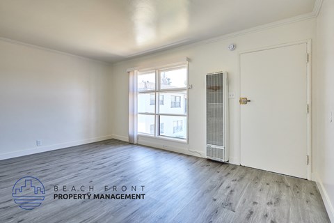 A room with a window and a door, managed by Beach Front Property Management.
