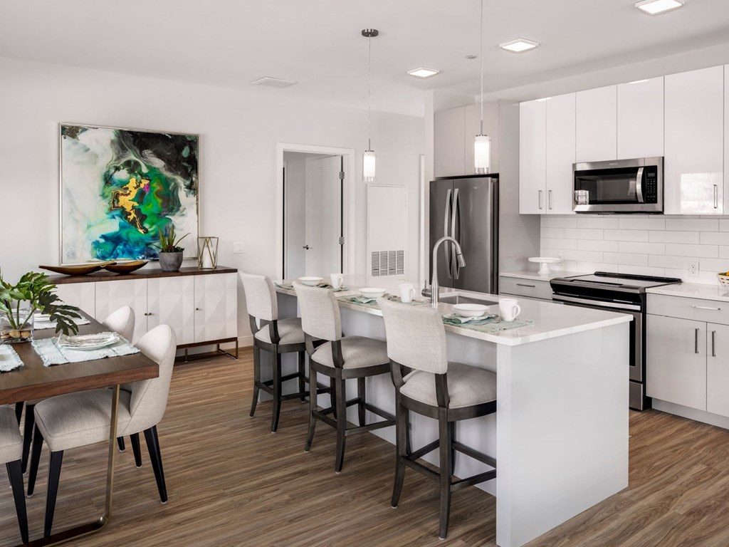 an open kitchen and dining room with white cabinets and a marble counter top