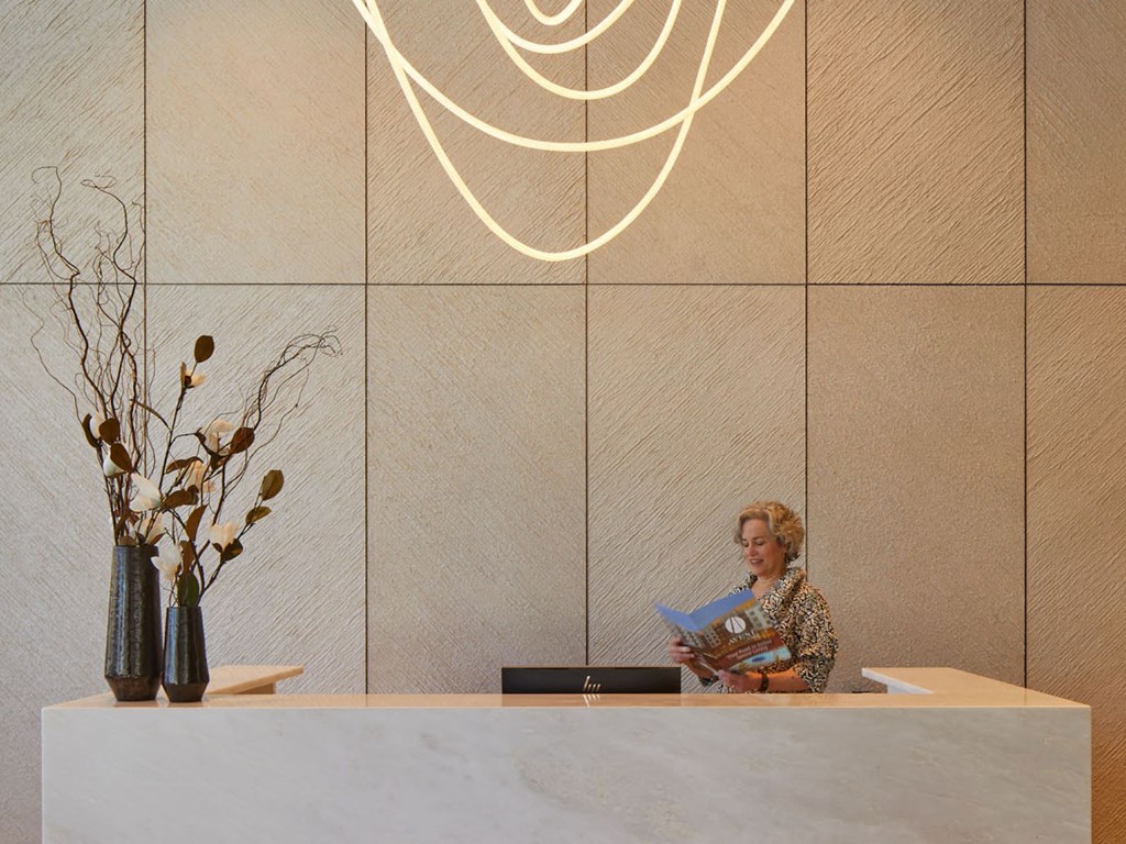 a woman sitting in the lobby of a hotel reading a magazine