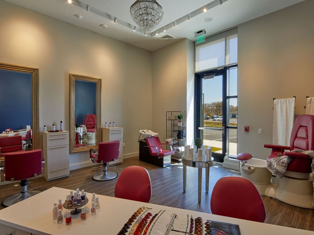 a salon room with red chairs and a table