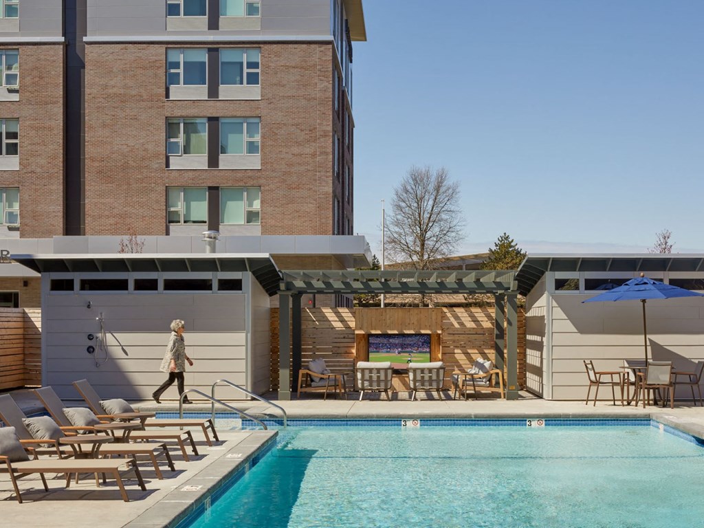 a woman walking next to a swimming pool in front of a building