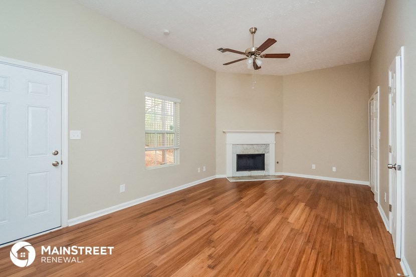 the living room with fireplace and wood flooring and a ceiling fan