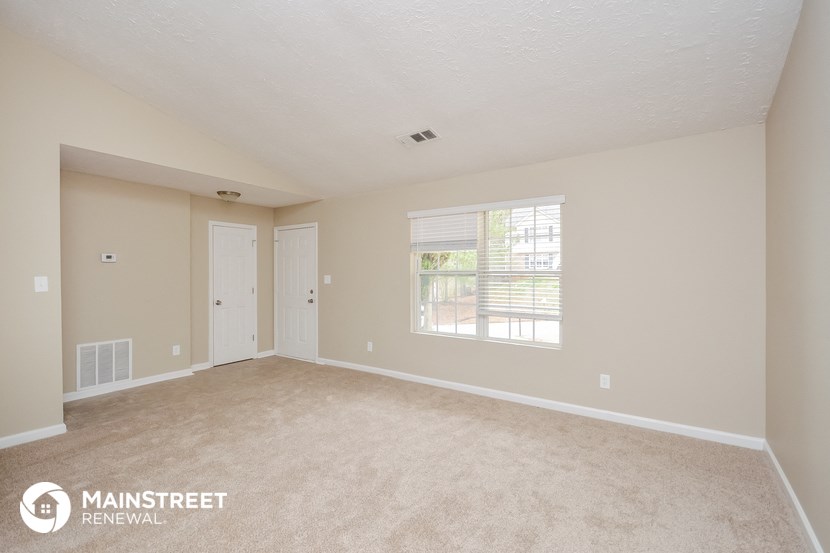 the spacious living room with carpeting and a large window