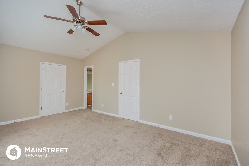 the spacious living room with carpeting and a ceiling fan