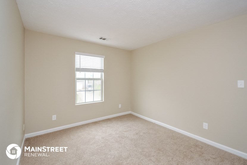 a bedroom with beige carpet and a window