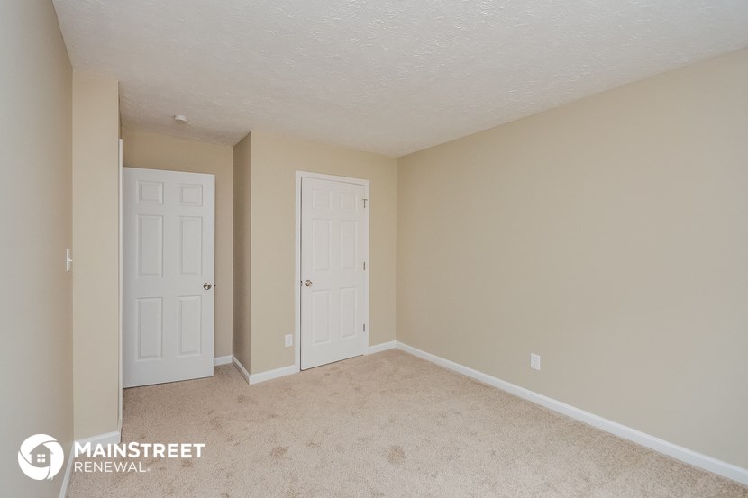 a bedroom with two doors and a carpeted floor