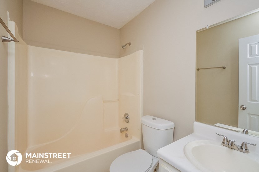a bathroom with a toilet sink and tub and a mirror