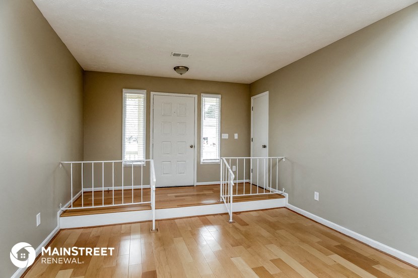 the living room of a home with two stairs and a white door