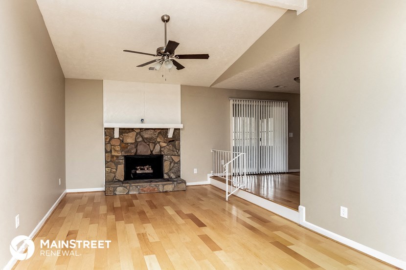 a living room with a fireplace and a ceiling fan