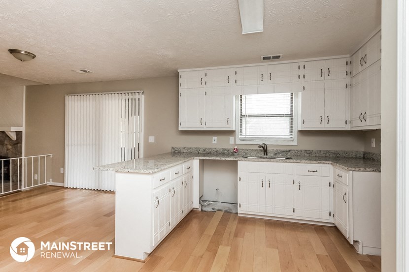a white kitchen with white cabinets and a wood floor