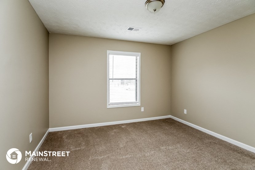 the spacious living room of this manufactured home has carpeting and a window
