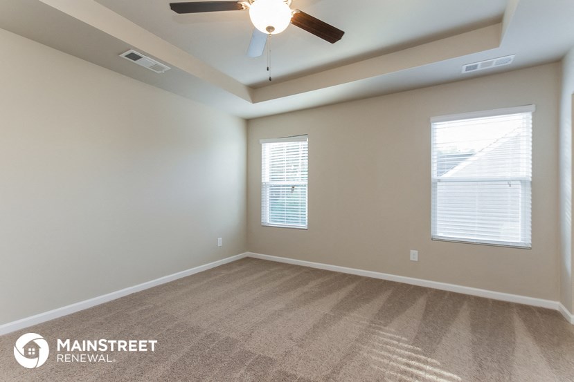 the spacious living room with carpet and ceiling fan