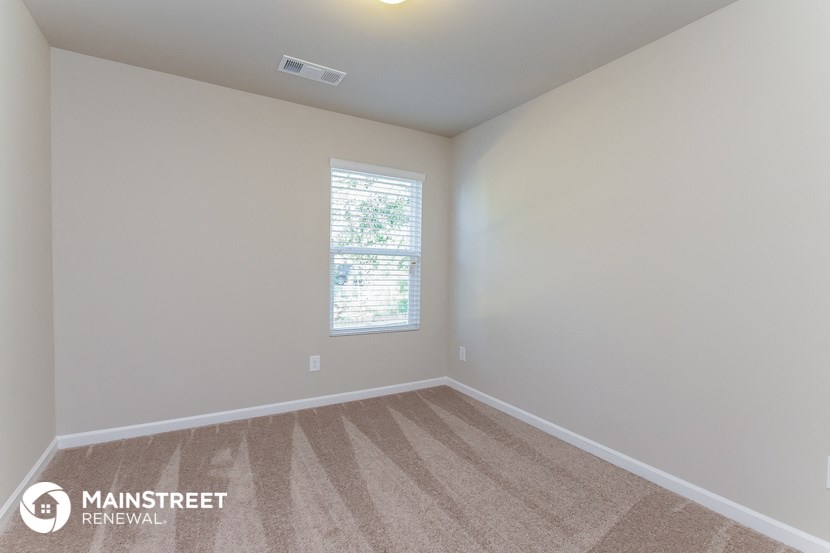 the spacious living room with carpeting and a window