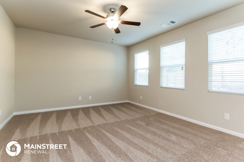 the spacious living room with carpeting and a ceiling fan