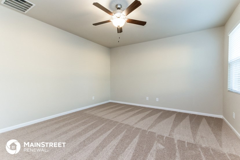 the spacious living room with ceiling fan and carpet