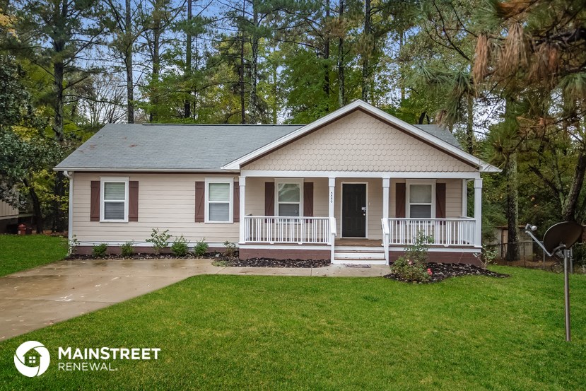 a small tan house with a porch and a lawn