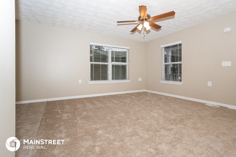 a living room with carpet and a ceiling fan