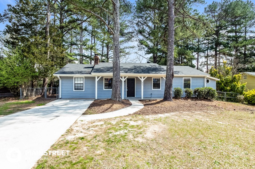 a blue house with a driveway and trees