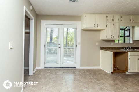 a kitchen with white cabinets and a door to a patio