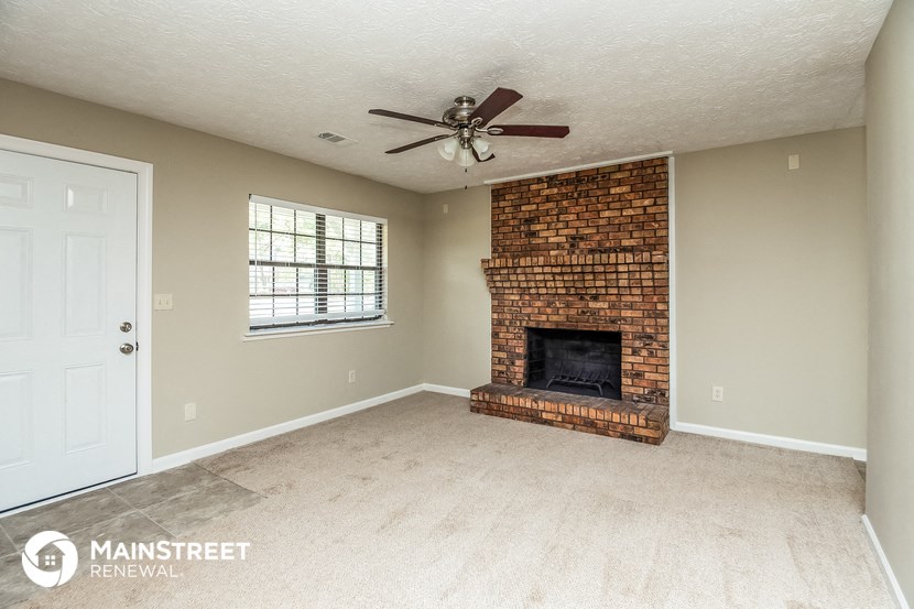 a living room with a brick fireplace and a ceiling fan