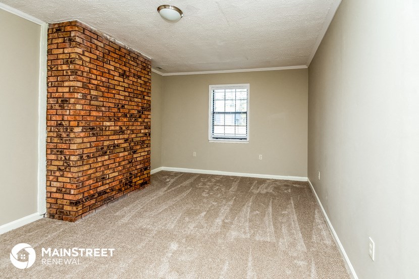 an empty room with a brick wall and a window
