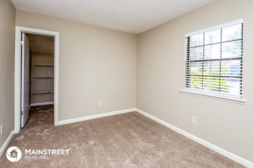 an empty room with a window and a door to a closet