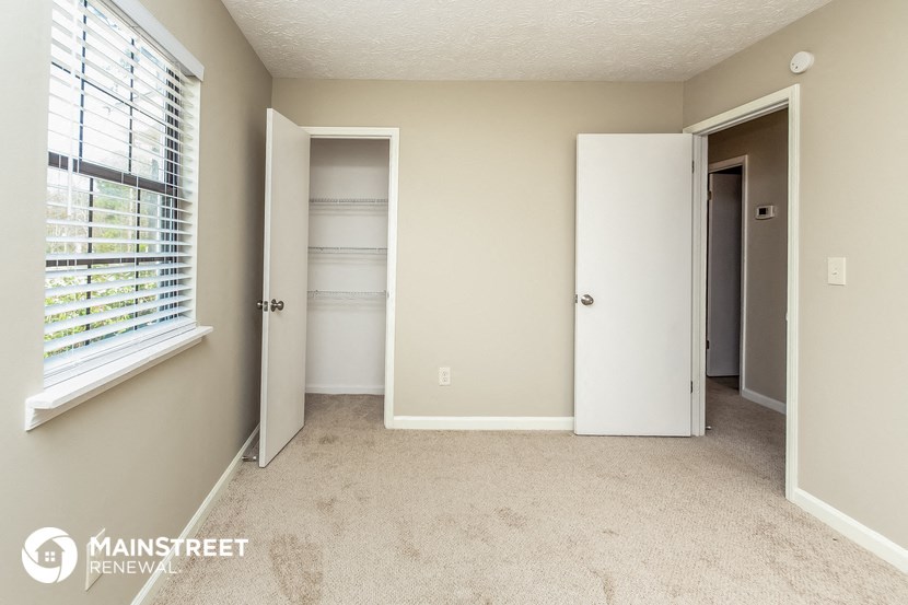 a bedroom with a closet and a window and a carpeted floor