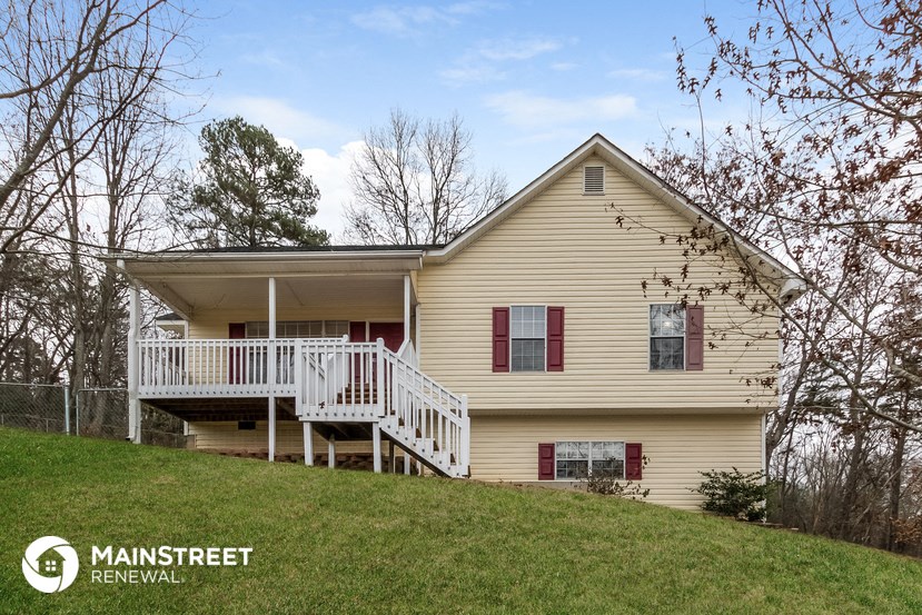 a yellow house with a white deck on top of a hill
