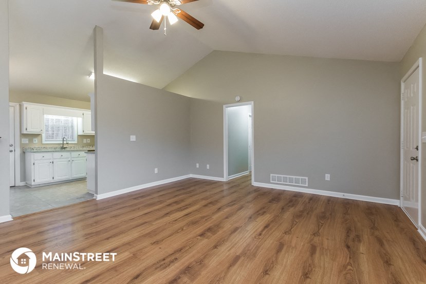 the living room and kitchen of an empty house with wood flooring